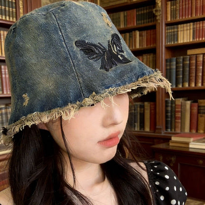 Person wearing a denim bucket hat with a black flower design in a library setting