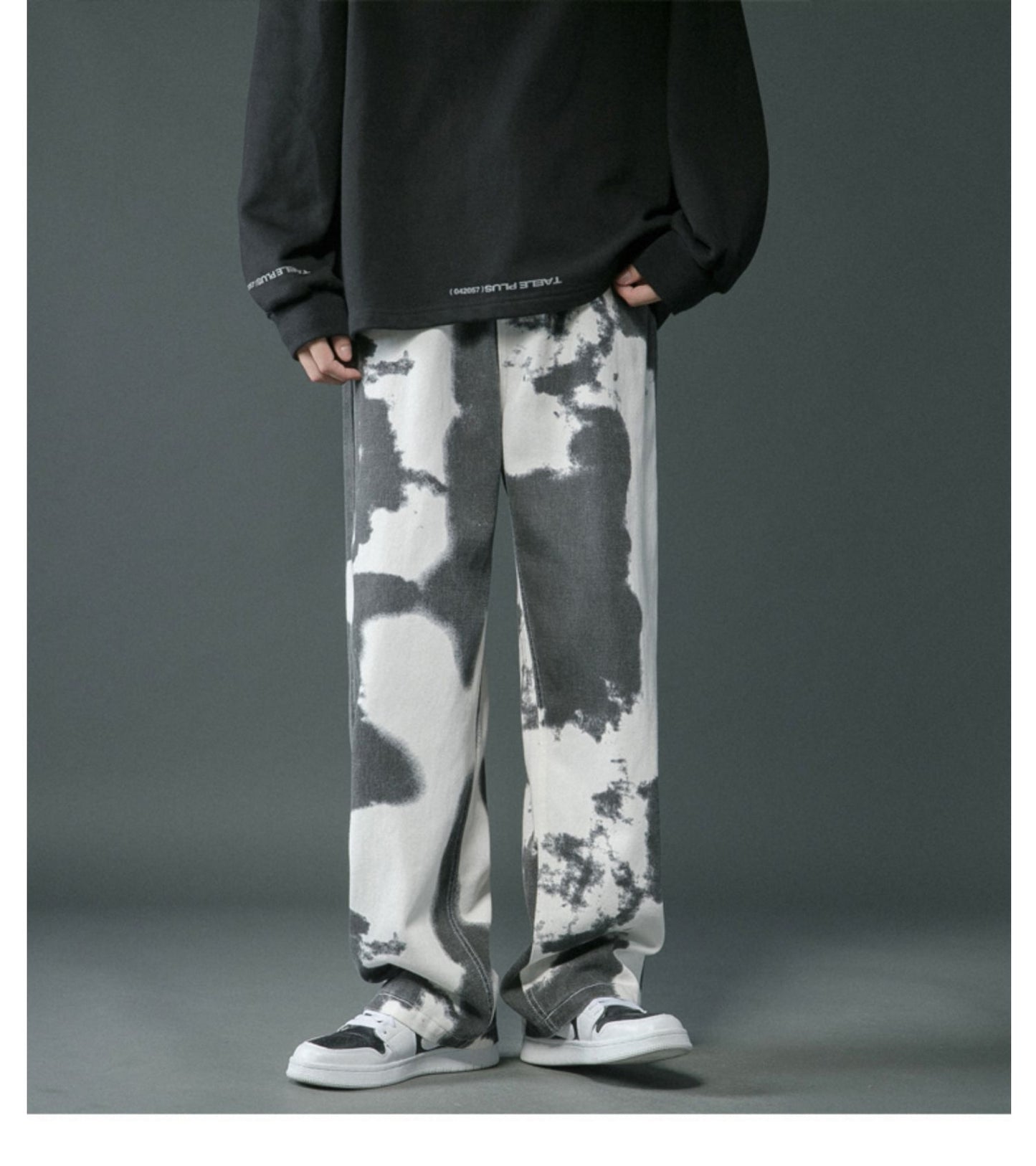 Person wearing black and white tie-dye pants with a dark background