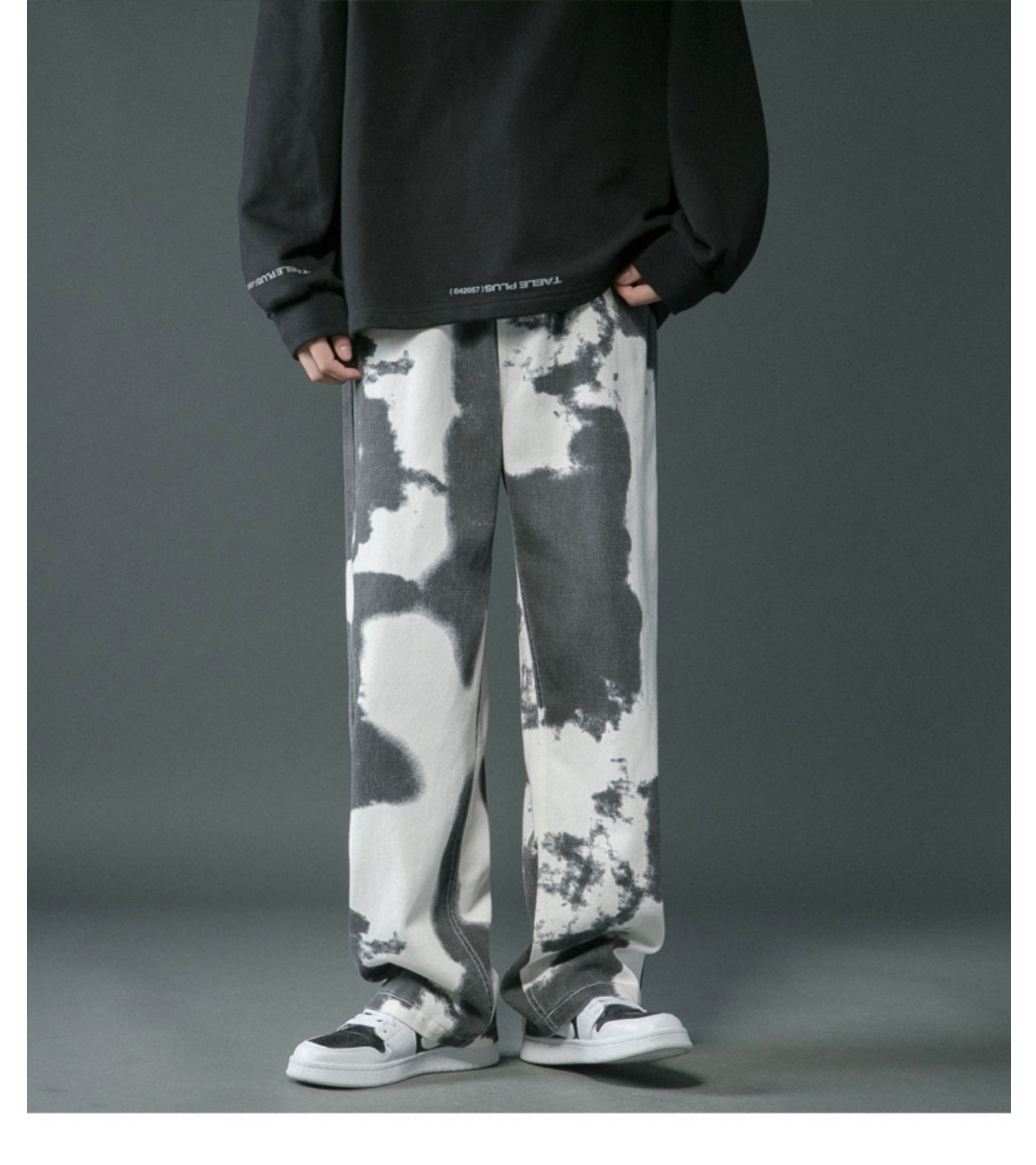 Person wearing black and white tie-dye pants with a dark background