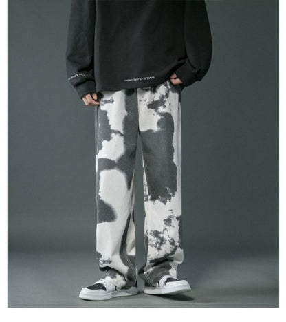 Person wearing black and white tie-dye pants with a dark background