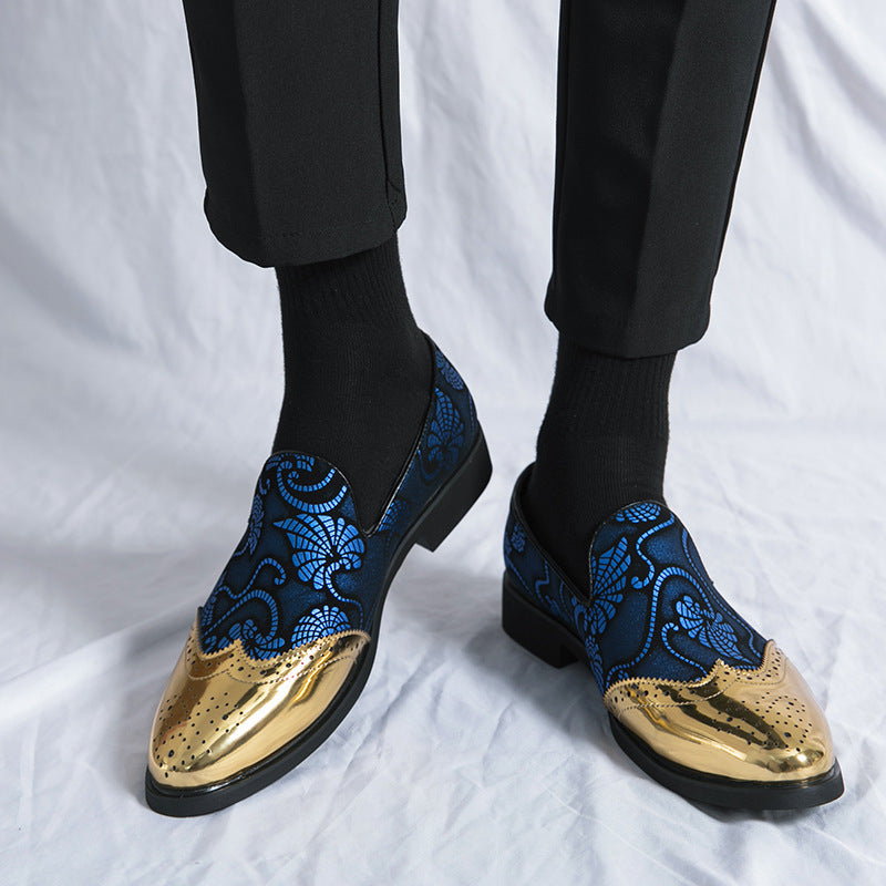 Blue embroidered loafers with gold toes worn by a person on a white background