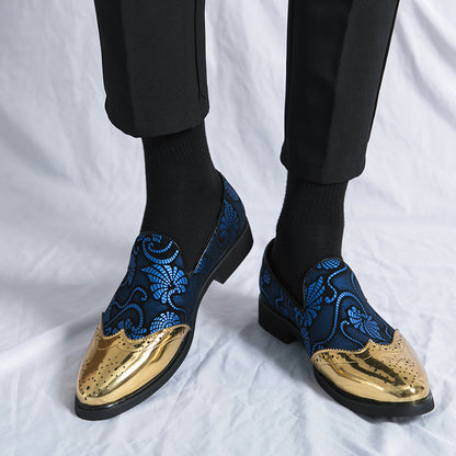 Blue embroidered loafers with gold toes worn by a person on a white background