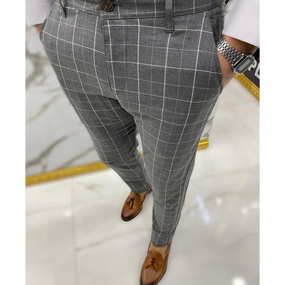 Gray checkered pants worn by a person on a reflective floor.