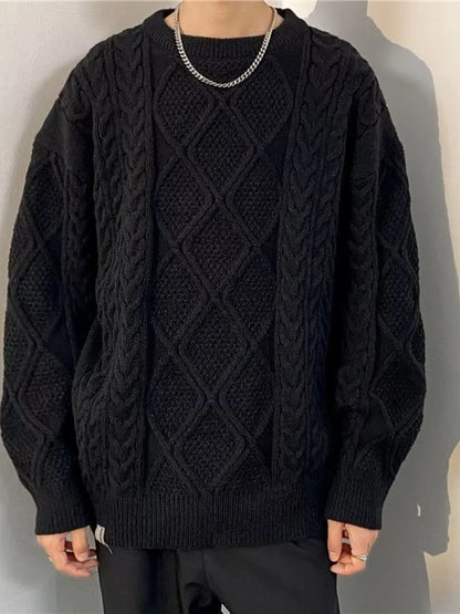 Person wearing a black cable knit sweater against a plain background