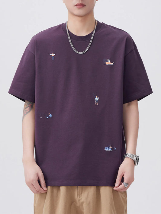 Person wearing a dark purple t-shirt with small embroidered designs on a plain background