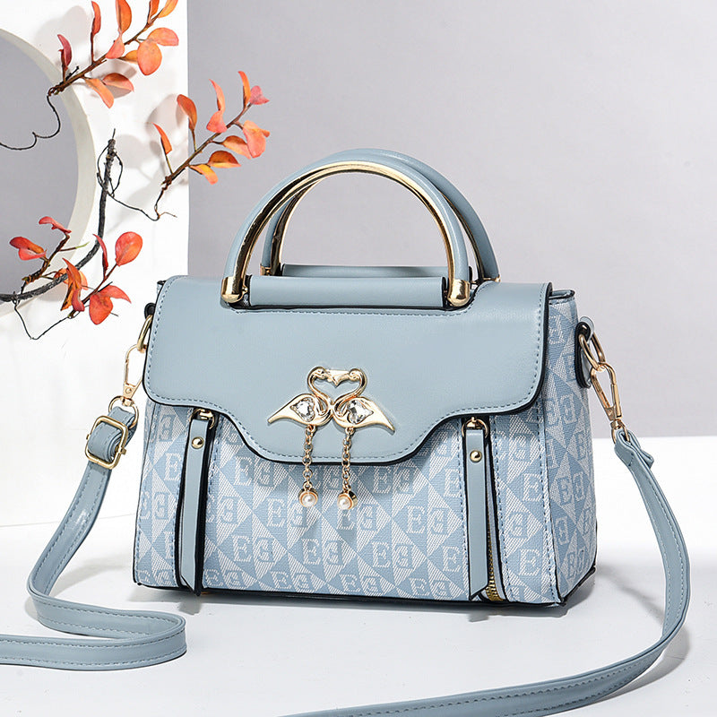 Light blue handbag with gold accents on a white background