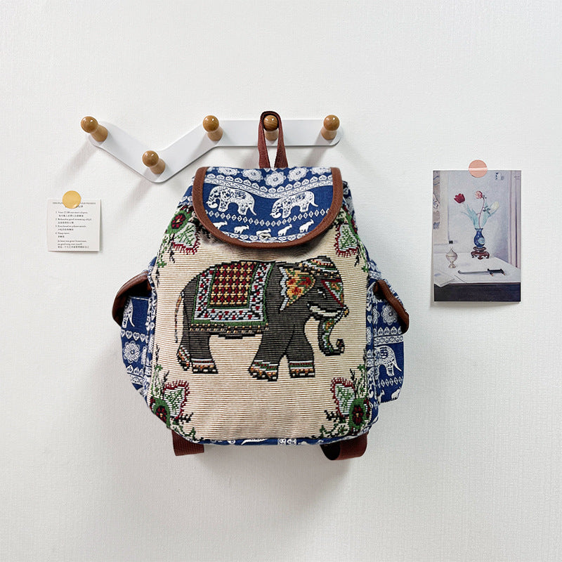 Backpack with elephant design hanging on a wall hook against a white background