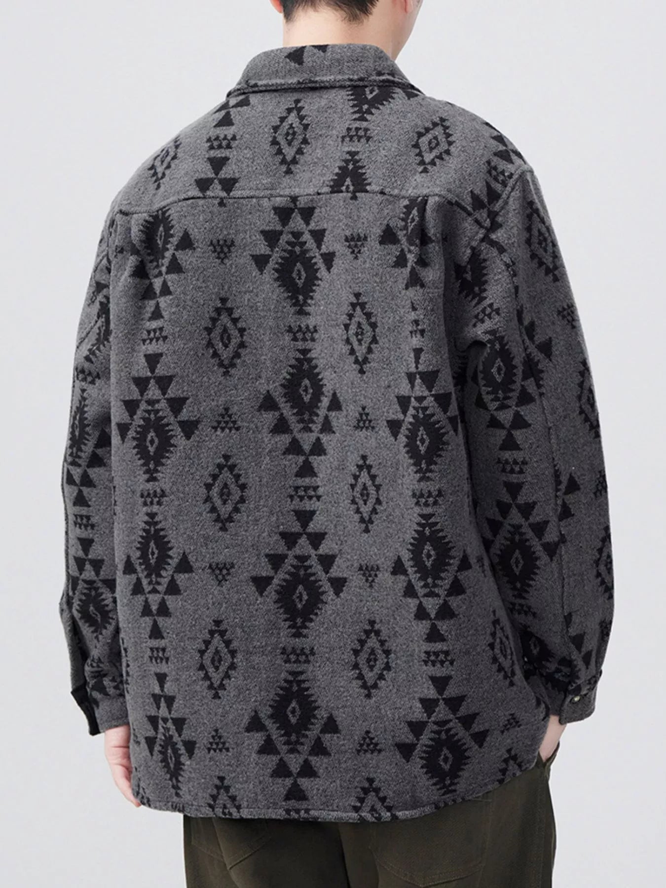 Person wearing a dark gray patterned shirt against a white background