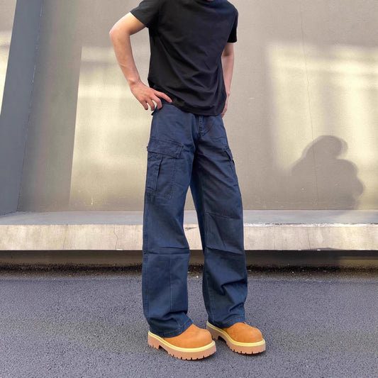 Person wearing navy cargo pants and brown boots standing on a pavement.