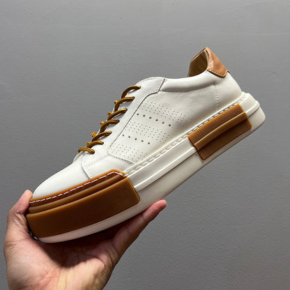 White sneaker with brown accents held against a gray background
