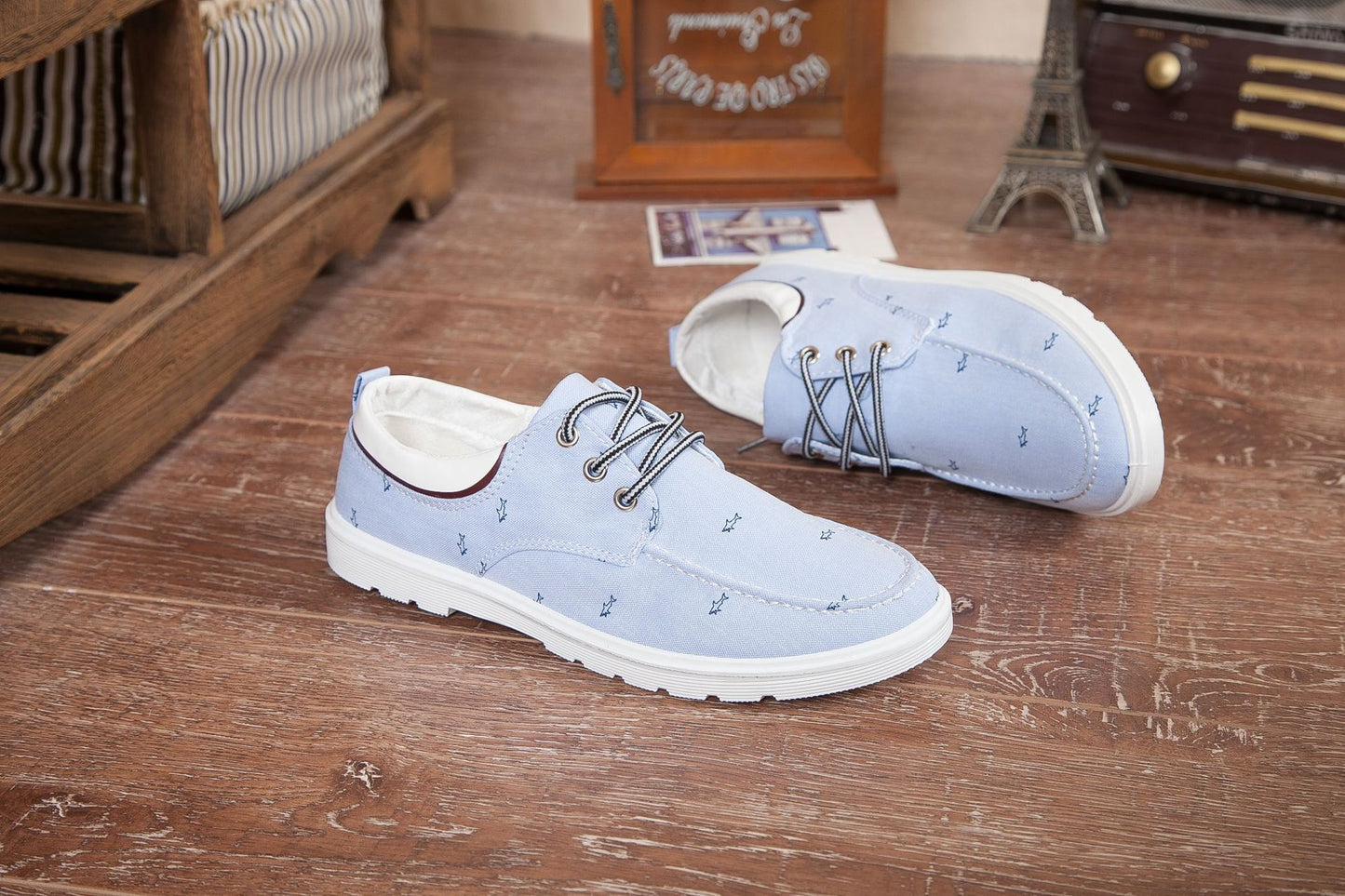 Pair of light blue shoes on a wooden floor with decorative items in the background.