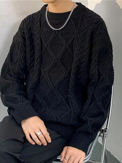 Person wearing a black cable knit sweater sitting on a chair.