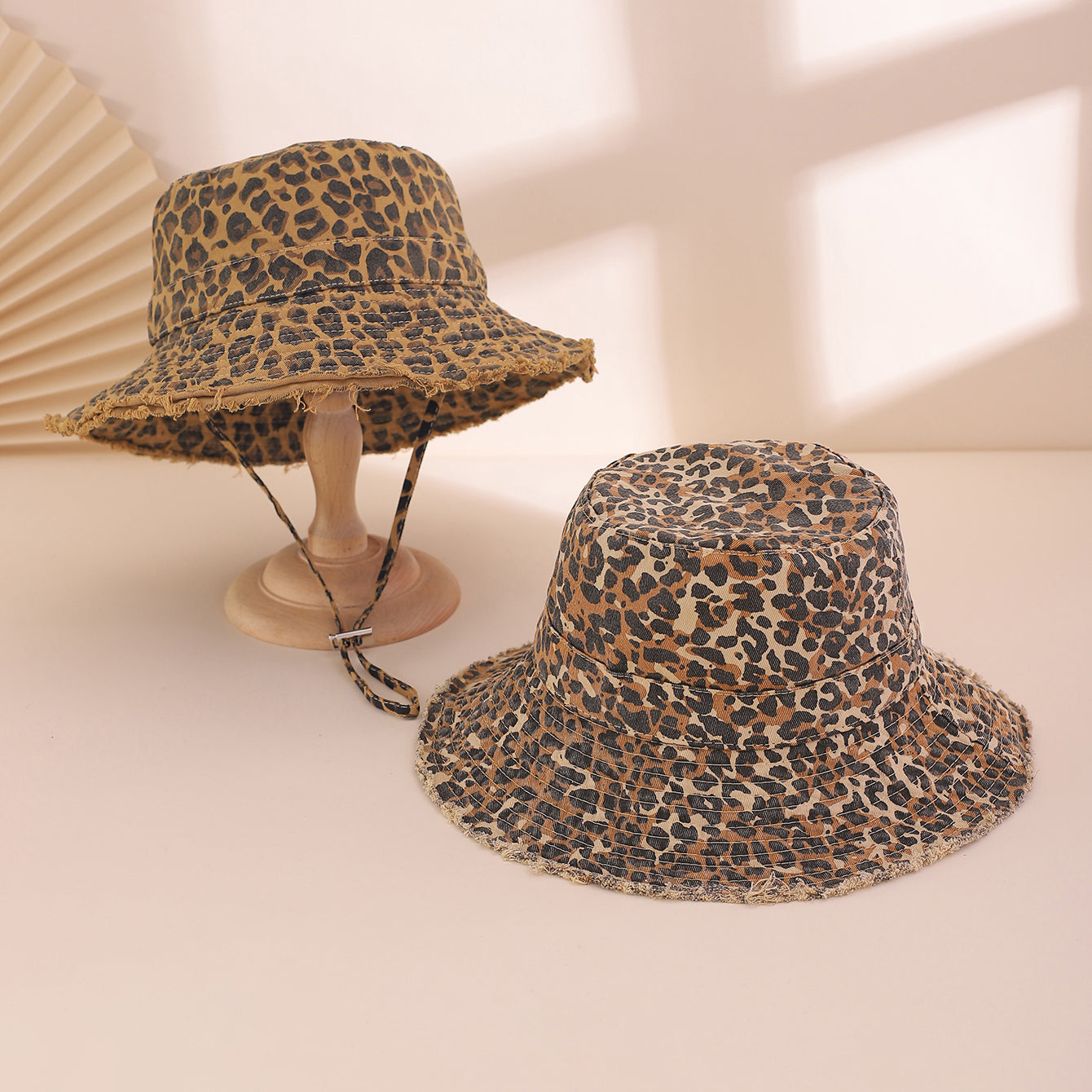 Two leopard print bucket hats on a light background