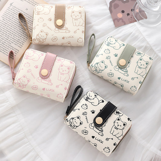 Four small wallets with cat illustrations on a white surface