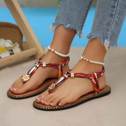 Colorful sandals with decorative straps worn by a person sitting by a pool.