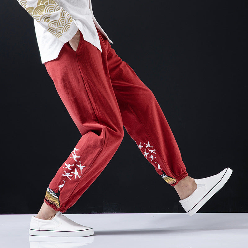 Person wearing red pants with white patterns and white sneakers on a black background