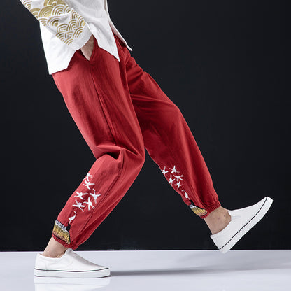 Person wearing red pants with white patterns and white sneakers on a black background
