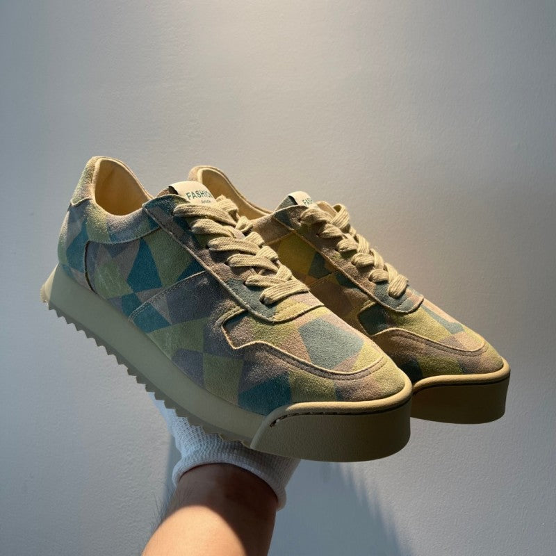 Pair of patterned sneakers held against a plain background