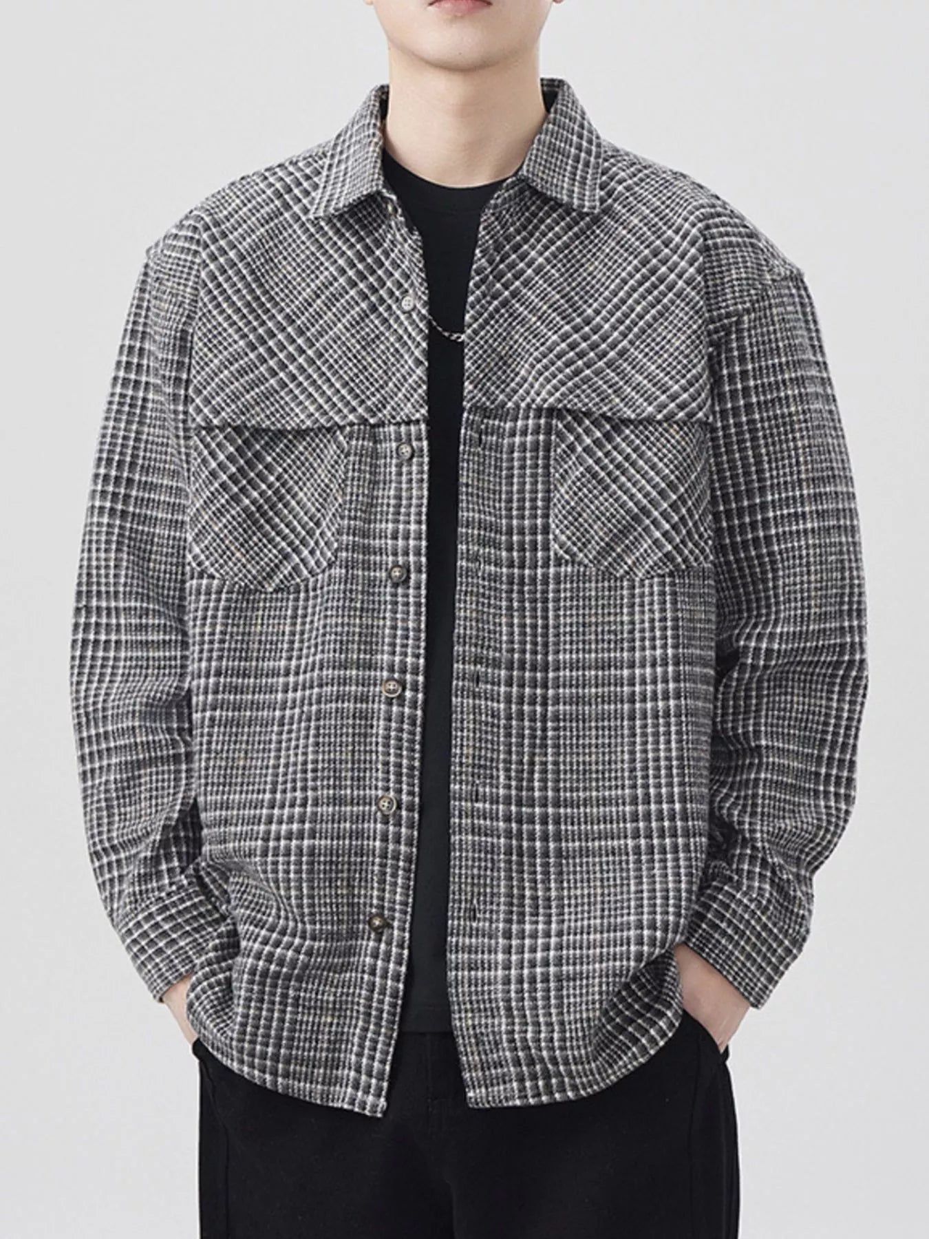 Person wearing a black and white checkered shirt on a plain background