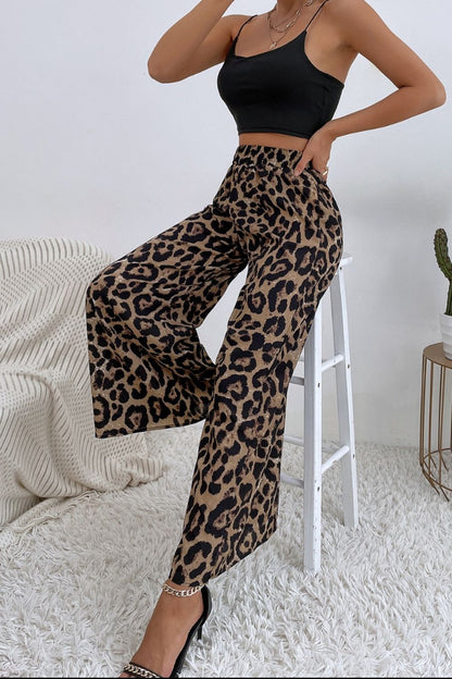 Person wearing leopard print pants and a black top in a minimalistic room.