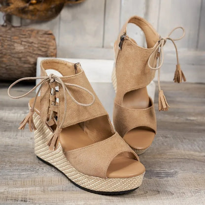 Pair of tan wedge sandals with raffia sole on a wooden surface