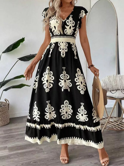 Woman wearing a black dress with white floral patterns in a room.