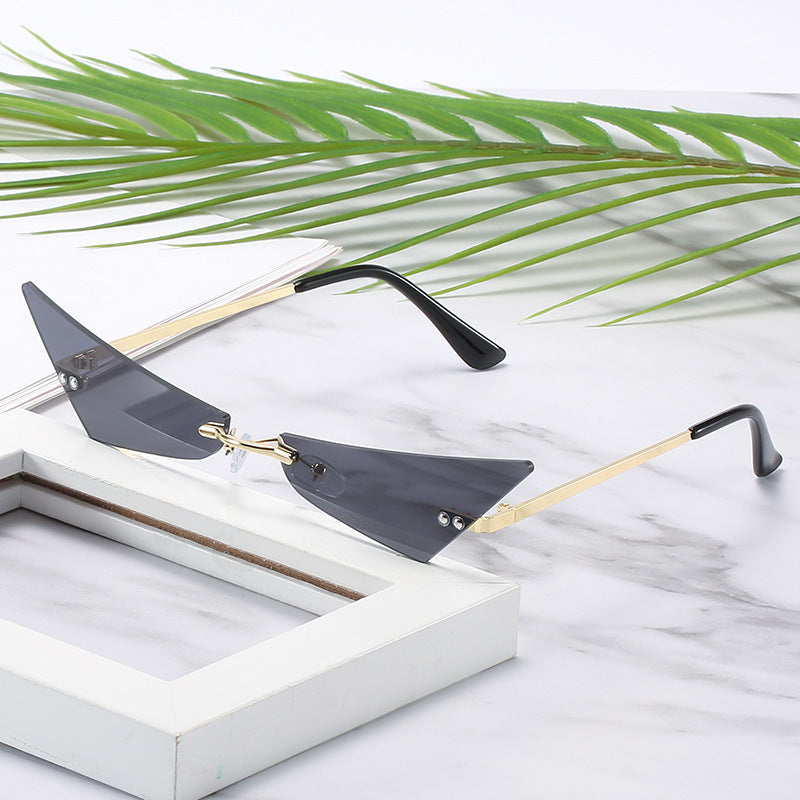 Sunglasses with gold and black frame on a marble surface with green leaves