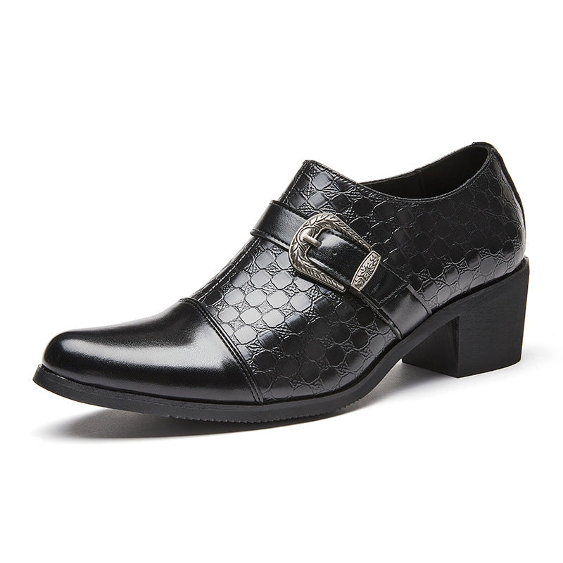 Black leather shoes with buckle details on a gray floor.