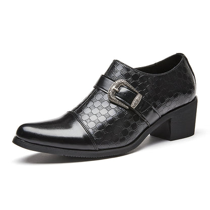 Black leather shoes with buckle details on a gray floor.