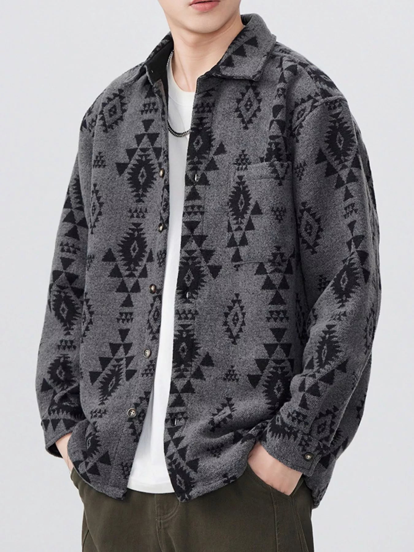 Person wearing a gray patterned shirt over a white t-shirt on a light gray background