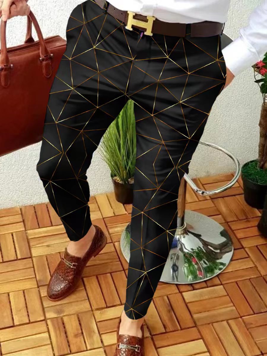 Person wearing black pants with gold geometric patterns, standing on a wooden floor.