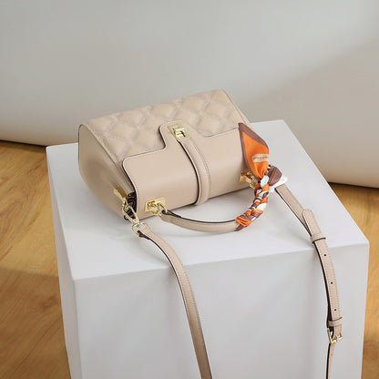 Beige handbag with a strap on a white pedestal