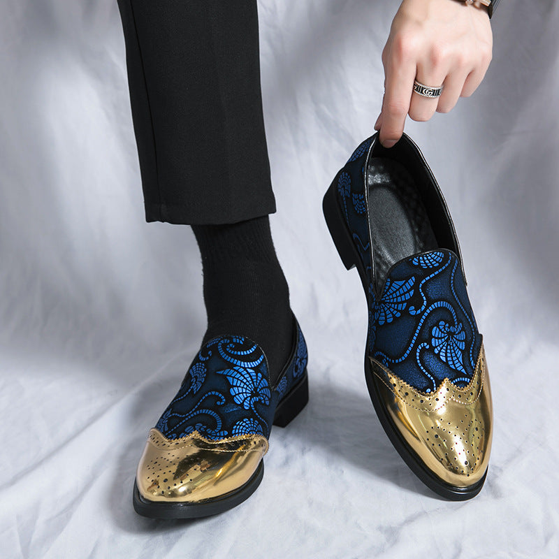 Blue embroidered loafers with gold accents worn by a person on a white background