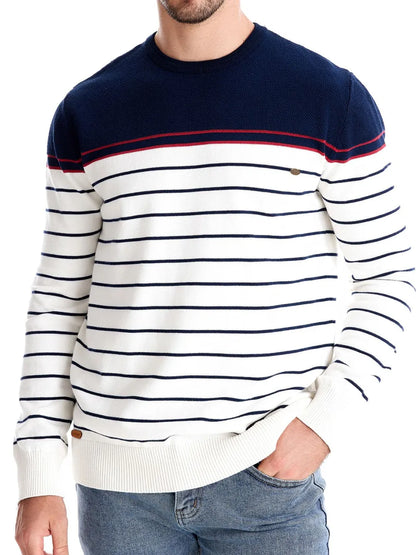 Man wearing a navy and white striped sweater with a red accent on a white background