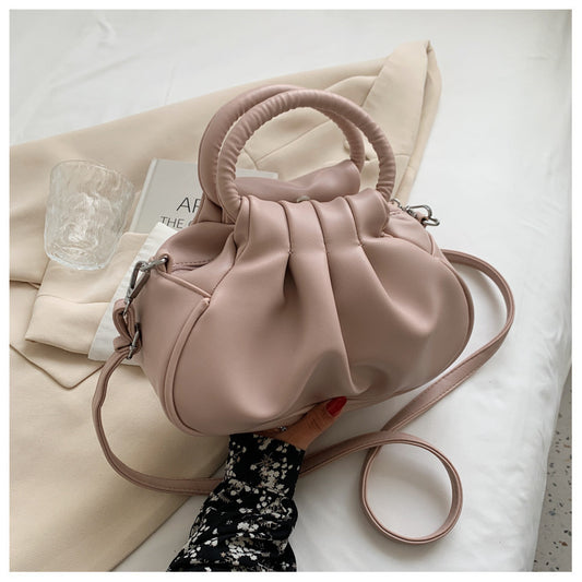 Pink handbag held by a hand on a light background