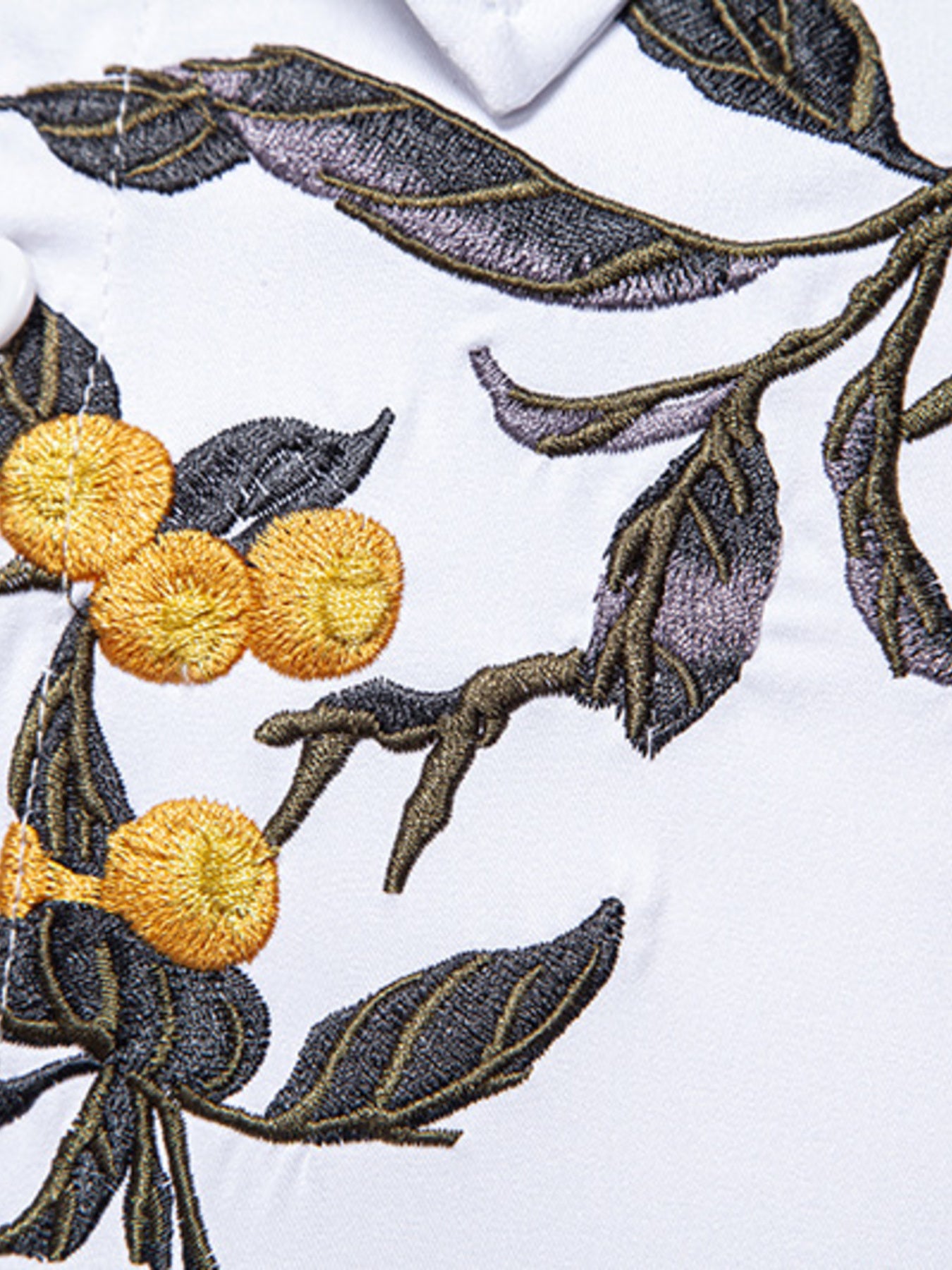 Embroidered design of oranges and leaves on a white fabric background