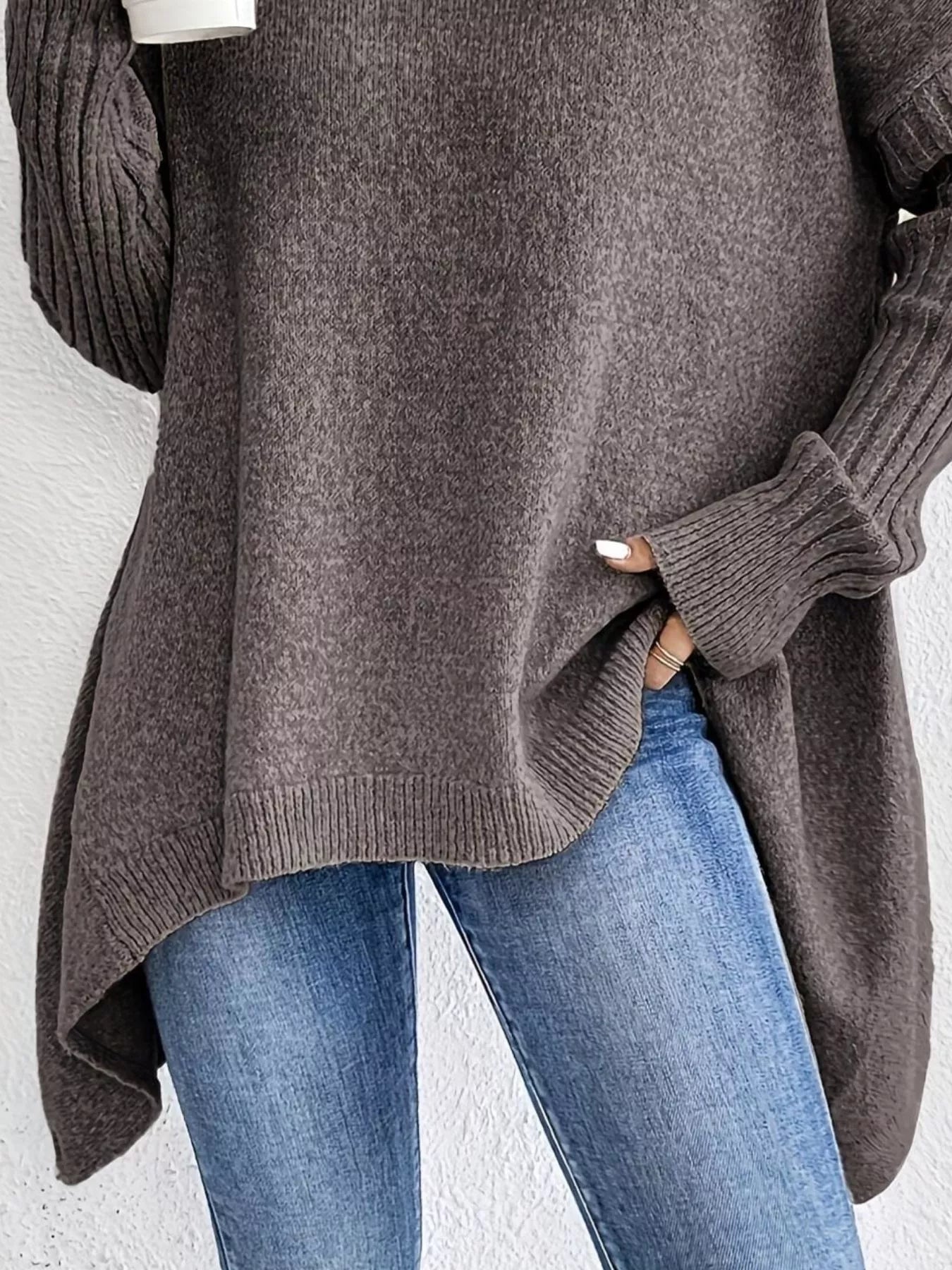 Person wearing a brown sweater and blue jeans against a white background