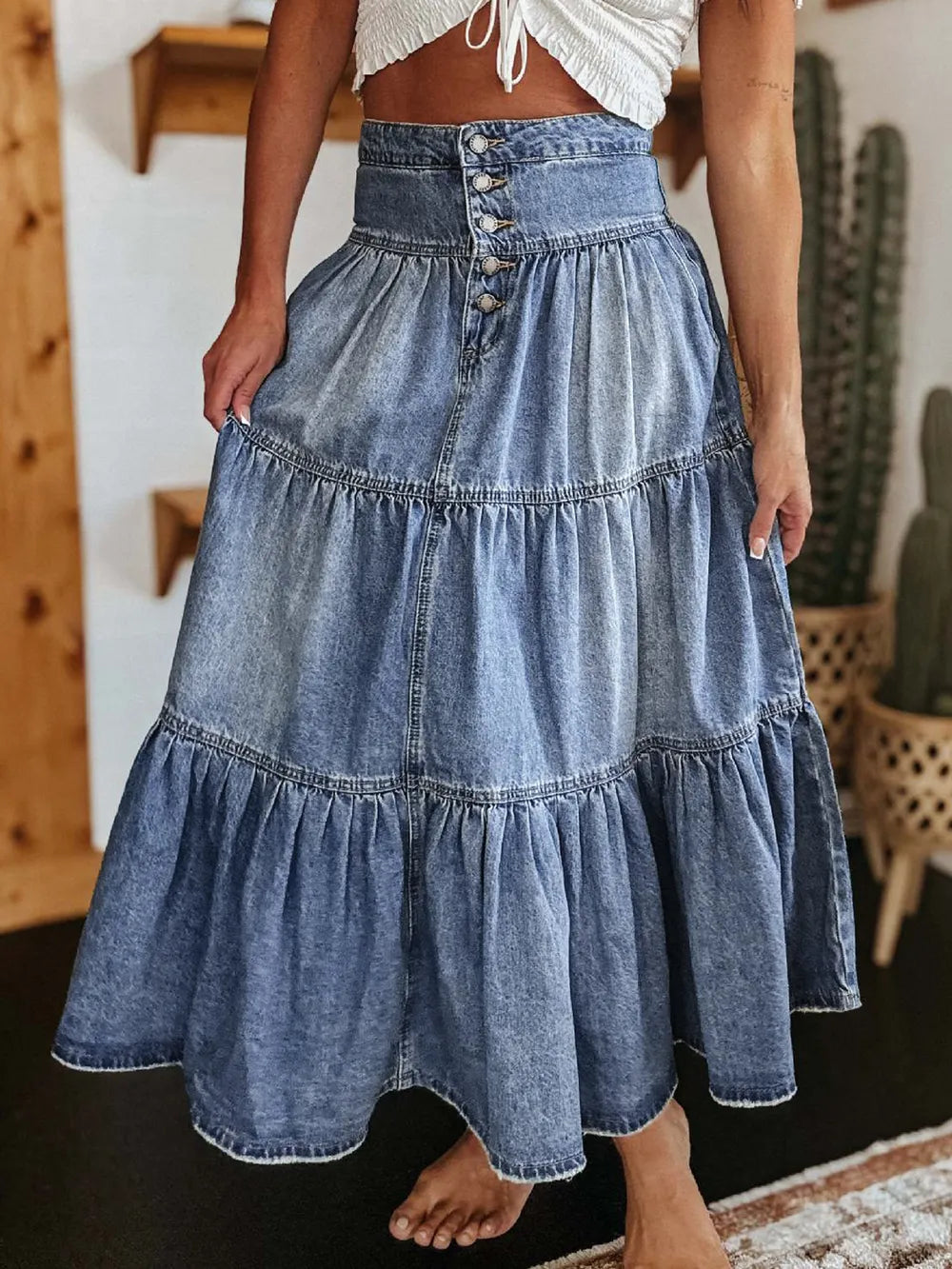 Denim skirt worn by a person indoors with wooden wall and cacti in the background