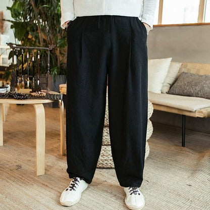 Person wearing black pants and white sneakers in a living room setting