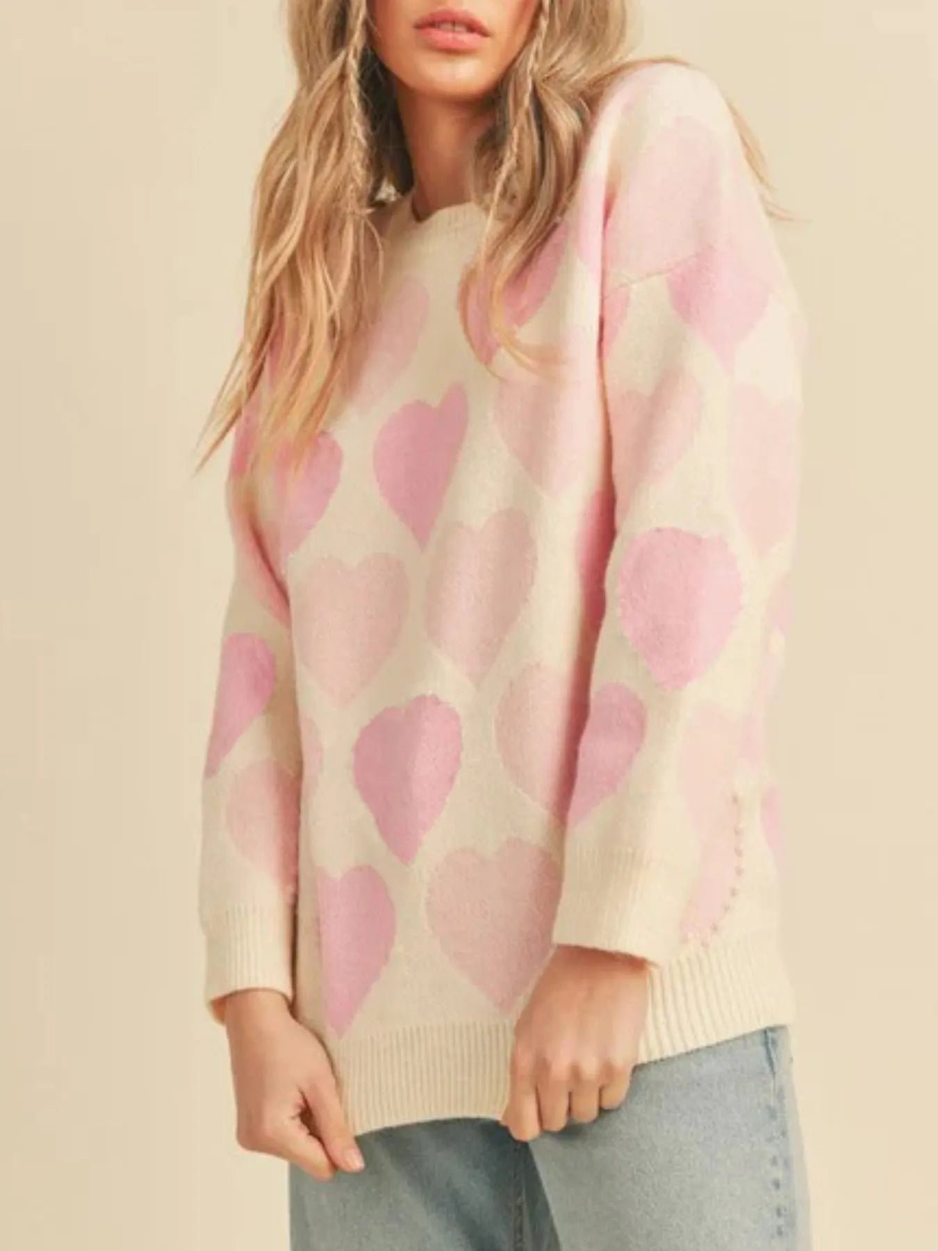 Woman wearing a sweater with pink hearts on a beige background