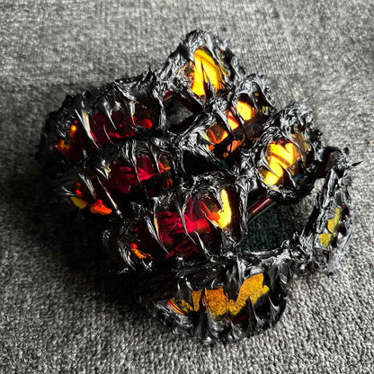 Decorative item resembling a dragon with glowing red and yellow eyes on a textured gray surface