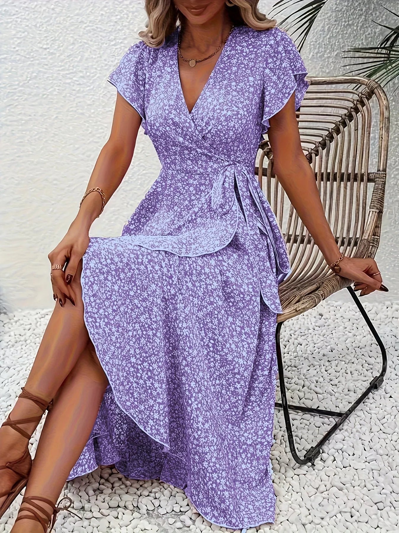 Woman wearing a purple floral dress sitting on a wicker chair.