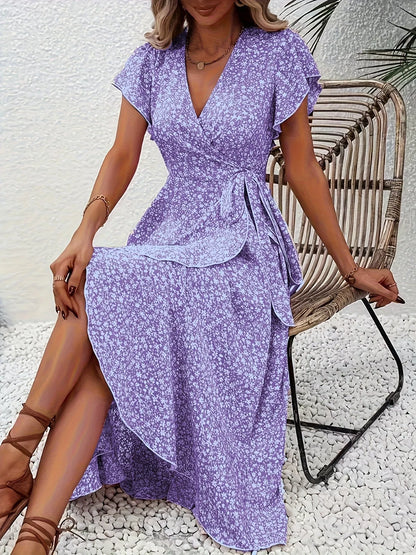 Woman wearing a purple floral dress sitting on a wicker chair.