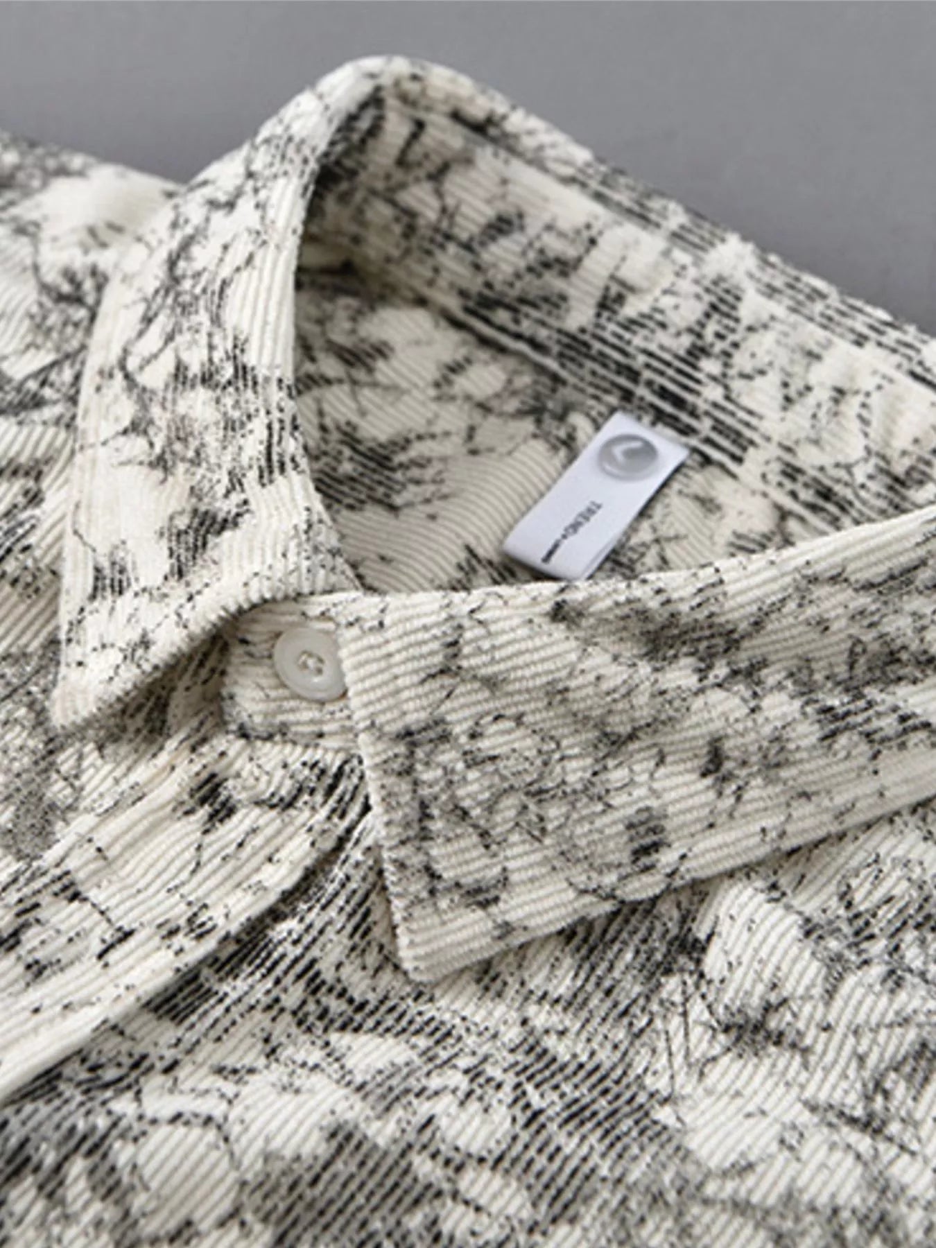 Folded patterned shirt with a label on a gray background
