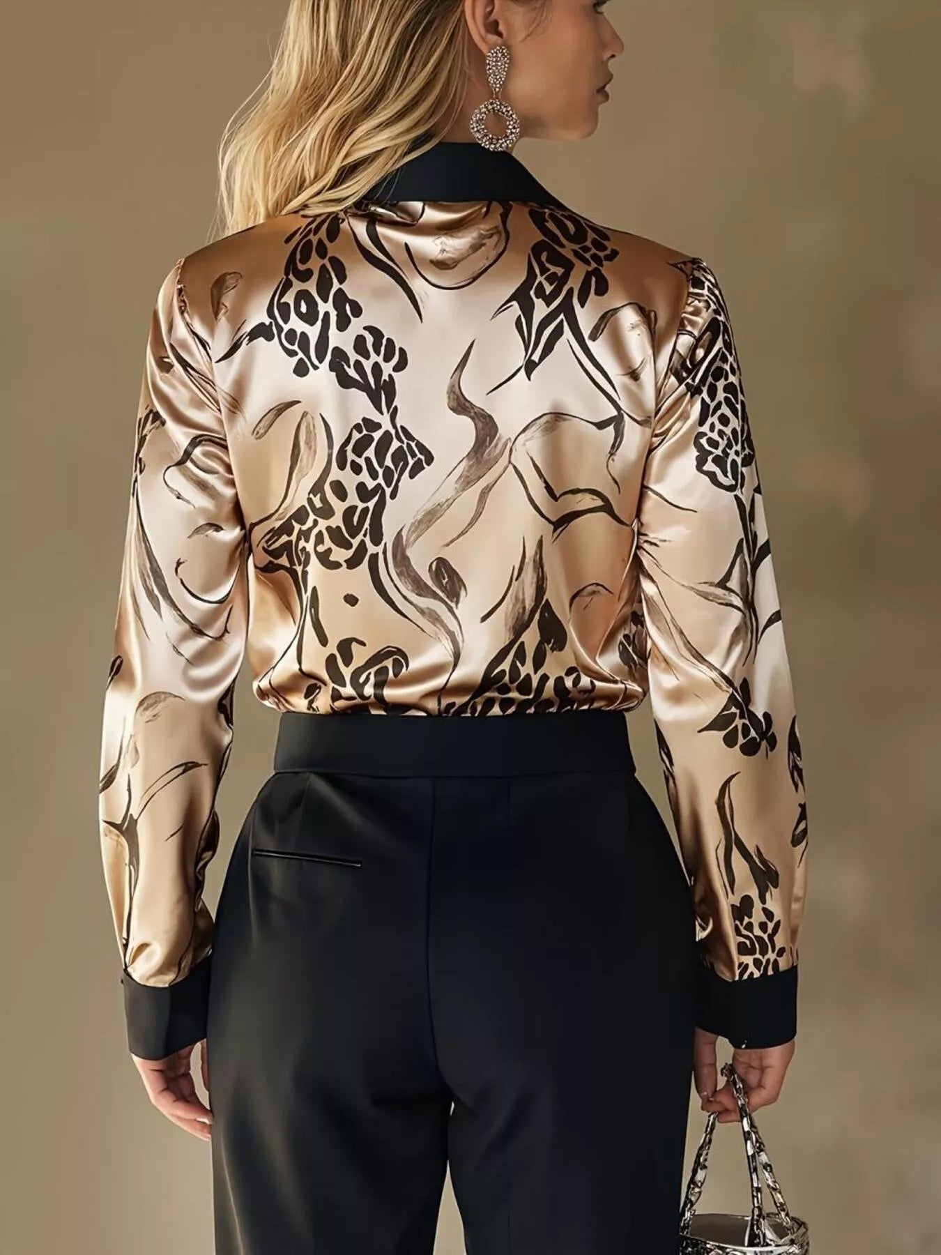 Woman wearing a patterned top and black pants against a neutral background