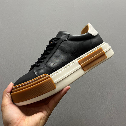 Black and white sneaker with brown accents held by a hand against a gray background