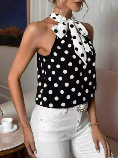 Woman wearing a black and white polka dot top with a bow neckline.