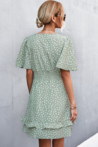 Woman wearing a green patterned dress against a gray wall