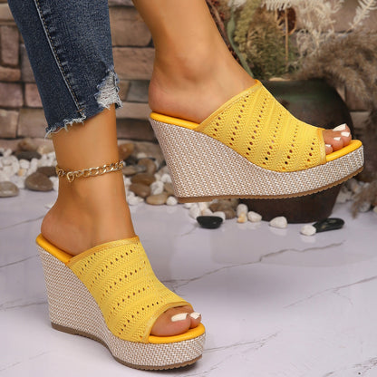 Yellow wedge sandals worn with denim jeans on a light stone floor.