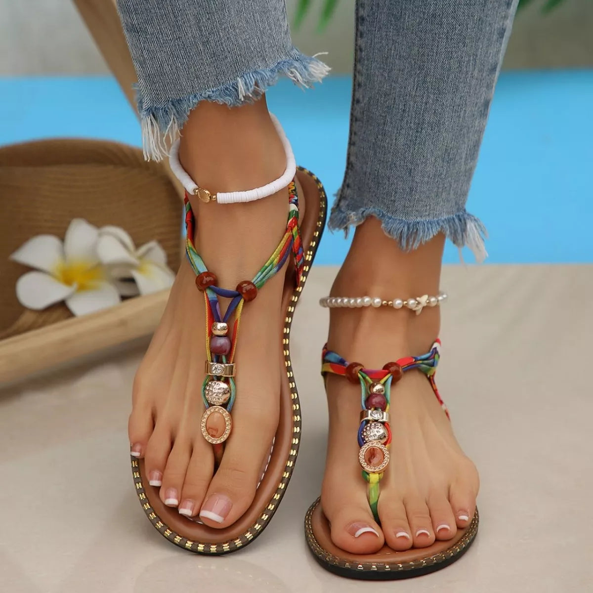 Colorful sandals with decorative straps worn by a person sitting by a pool.